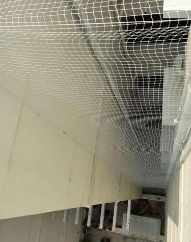 Wide-angle view showing a team installing safety nets on a multi-story building under construction.