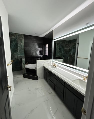 Modern master bathroom with white marble floors, a double vanity, and a black accent tile shower.