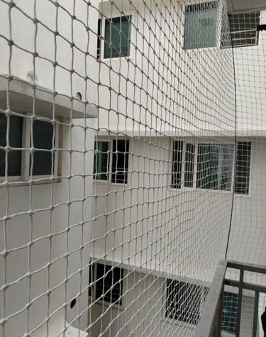 Close-up of a sturdy anti-pigeon safety net tightly secured on a balcony railing.