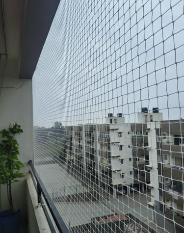 Close-up of a freshly installed black pigeon net on a modern Navi Mumbai balcony under sunlight