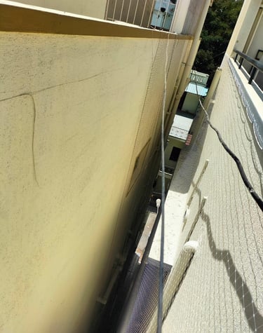 Wide view of a residential building with multiple pigeon nets installed by Arjilli Enterprises.