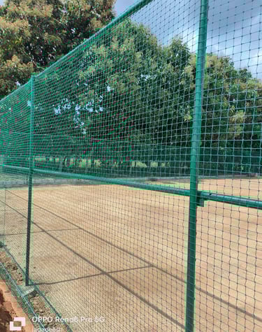 Technicians securing white sports nets with precision on a terrace in Bangalore.