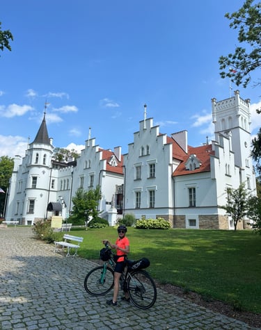 Karolina na rowerze przed białym pałacem. Rodzinna multiagencja ubezpieczeniowa Wrocław.