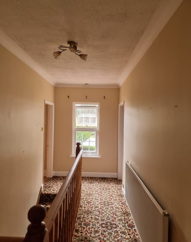 A cream-painted hallway, with a stairway leading down in a residential home.