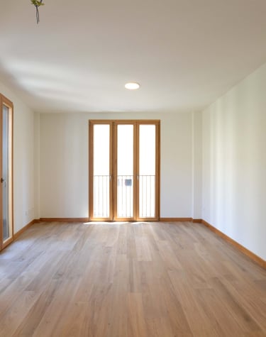 Balconeras de tres hojas mixtas aluminio-madera en salón vacío.