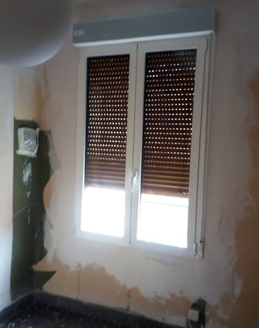 Ventana practicable de 2 hojas con lamas de persiana oscuras.