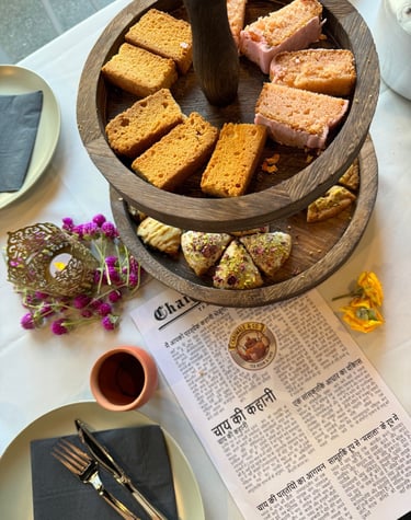 A tray at Afternoon Tea with Chai a Menu and Indian sweets and desserts