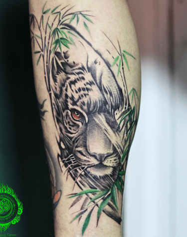 Realistic tattoo of a tiger with green bamboo on the calf
