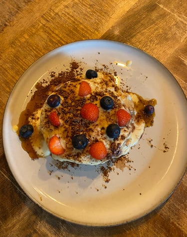 a plate of pancakes with berries on a table