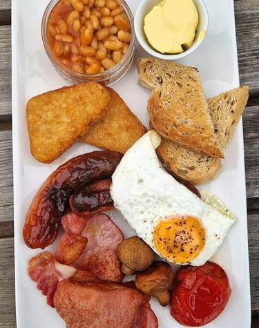 a full english breakfast with beans, butter, hash browns, toast, sausage, egg, bacon and tomato