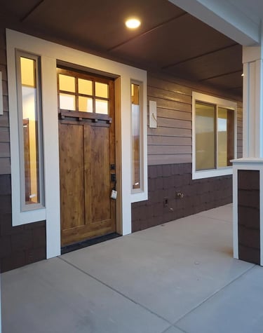 Wood front door and patio of newly finished custom home by Buck and Saddle Horn.