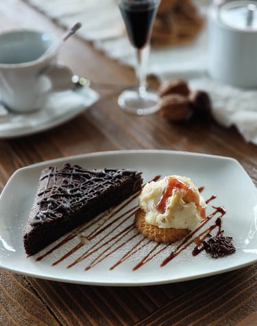 a piece of cake on a plate with a glass of wine