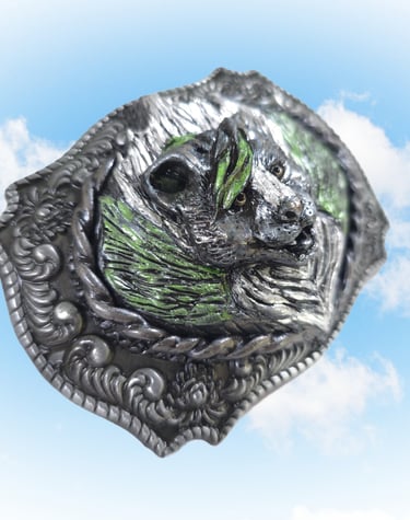 Vintage western silver bear belt buckle with green paint accents set against a blue sky background.