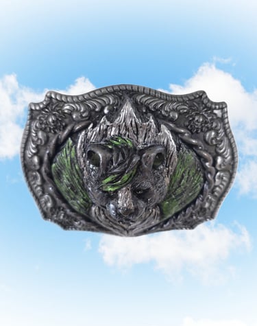 Vintage ornate skunk belt buckle with green enamel accents set against a blue sky background.