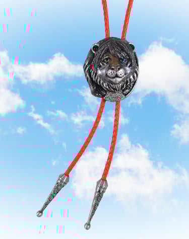Vintage silver lion head bolo tie with orange braided cord against a blue sky background.