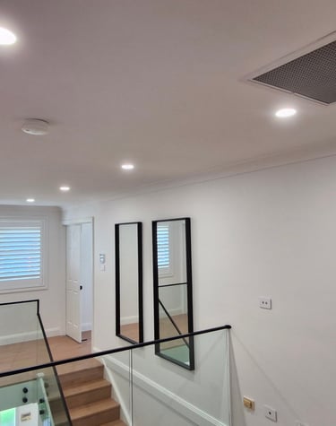 Modern home with recessed ceiling lights, glass staircase railing, and a white Clipsal smoke alarm