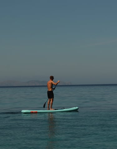 Persona practicando paddle surf en aguas tranquilas frente a la costa de Alcudia