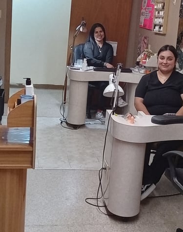 Student nail technicians sitting at individual manicure stations in a college beauty salon.
