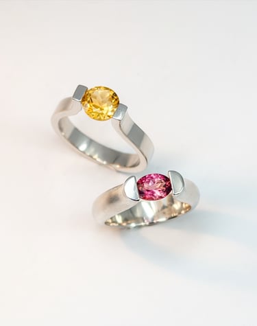 a pair of tension set sterling silver rings set with a pink tourmaline and the other a citrine.