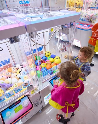 young kids playing a claw machine