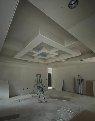 a room in the process of having drywall installed on the ceiling with work ladders