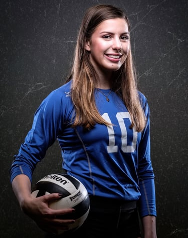 a woman in a blue shirt and shorts holding a volleyball ball