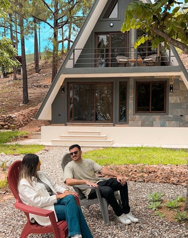 a man and woman sitting on a bench in front of a house
