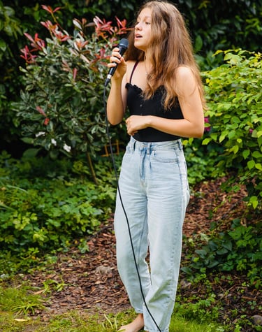 ein Mädchen, das in ein Mikrofon singt - im Garten