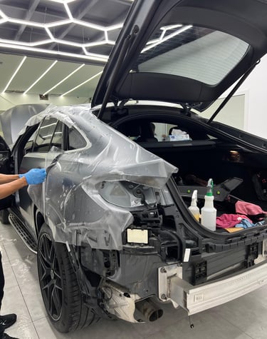 Professional installer applying a paint protection film to a luxury car for auto detailing.