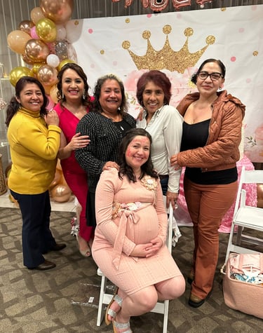A group of happy women celebrate at a royal-themed baby shower with gold balloons and a princess crown backdrop.