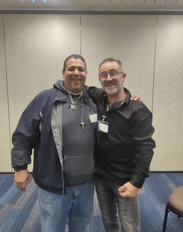 Two smiling men in casual attire posing together at a professional conference event.