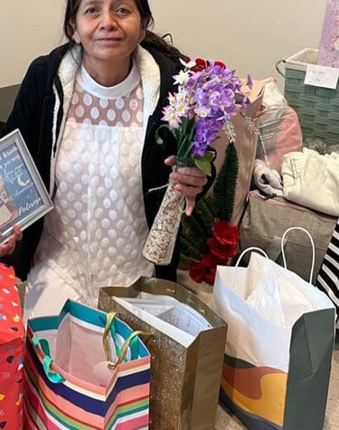 Smiling woman holding purple artificial flowers and gifts for a special celebration.