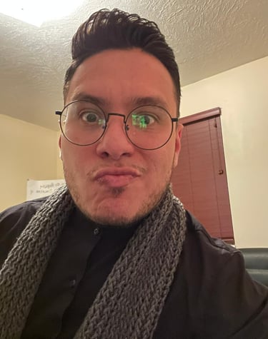 A man wearing round glasses and a grey knitted scarf making a funny face for a close-up portrait.