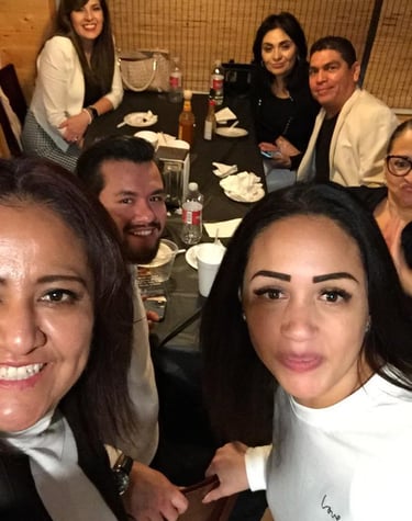 A group of happy friends taking a selfie while dining together at a restaurant table.