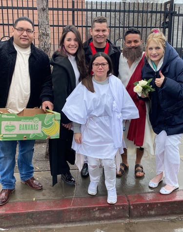A diverse group of friends in white and red costumes pose together outdoors by a fence.