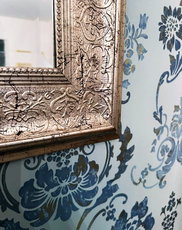 burnished silver mirror frame and soft teal wallpaper