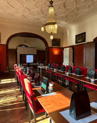 Elegant conference room with red chairs, crystal chandelier, and gift bags for a luxury corporate event.