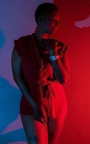 a woman in a red dress standing in front of a red light boudoir shoot