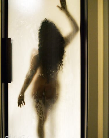 Louisiana boudoir model in a bathing suit is standing in front of a shower