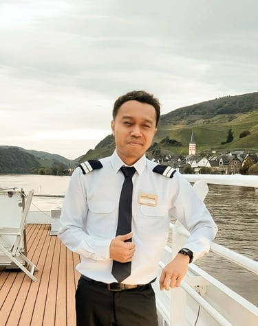 A Head Housekeeper in uniform standing on a deck overlooking a river village.