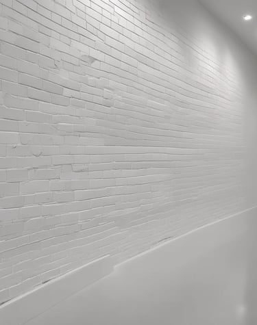 Building exterior mid-clean, with grime washing away to reveal fresh brickwork under a clear blue sky.
