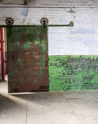 Original iron sliding door, peeling paint of the textured walls and stone floor in the Stone Room at Atlas Studios