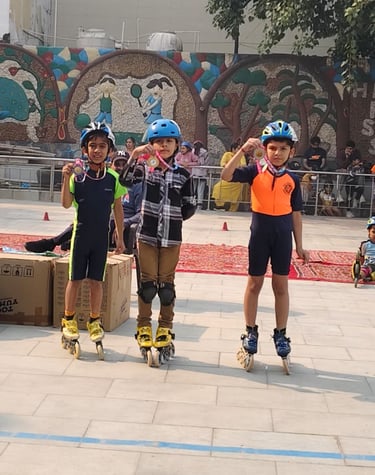 Three young boys in safety gear showing their medals at an outdoor inline skating competition.