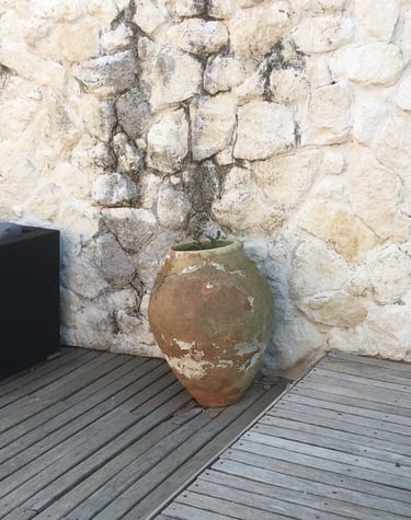 itahome Rustic terracotta clay amphora jar on a wooden deck against a natural white stone wall.
