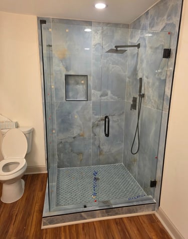 Modern bathroom featuring a walk-in glass shower with blue marble tiles and a black rainfall showerhead.