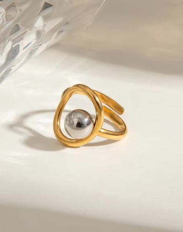 Anillo dorado minimalista con diseño escultórico y esfera central, joyería elegante de Moreina Joyería.