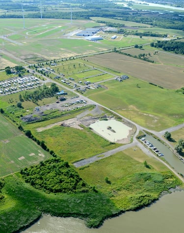 Aerial view of a rural campground and boat launch area near wind turbines and river wetlands.