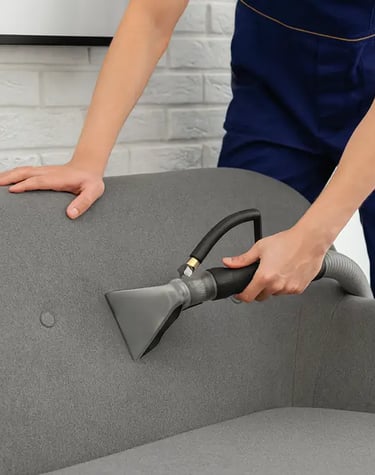 a person cleaning a couch with a vacuum