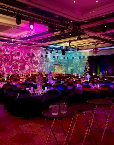 A corporate holiday party featuring lots of audiovisual gear at a convention centre in a ballroom.