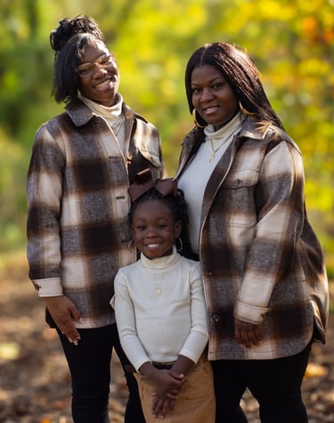 a family of three standing in a wooded area